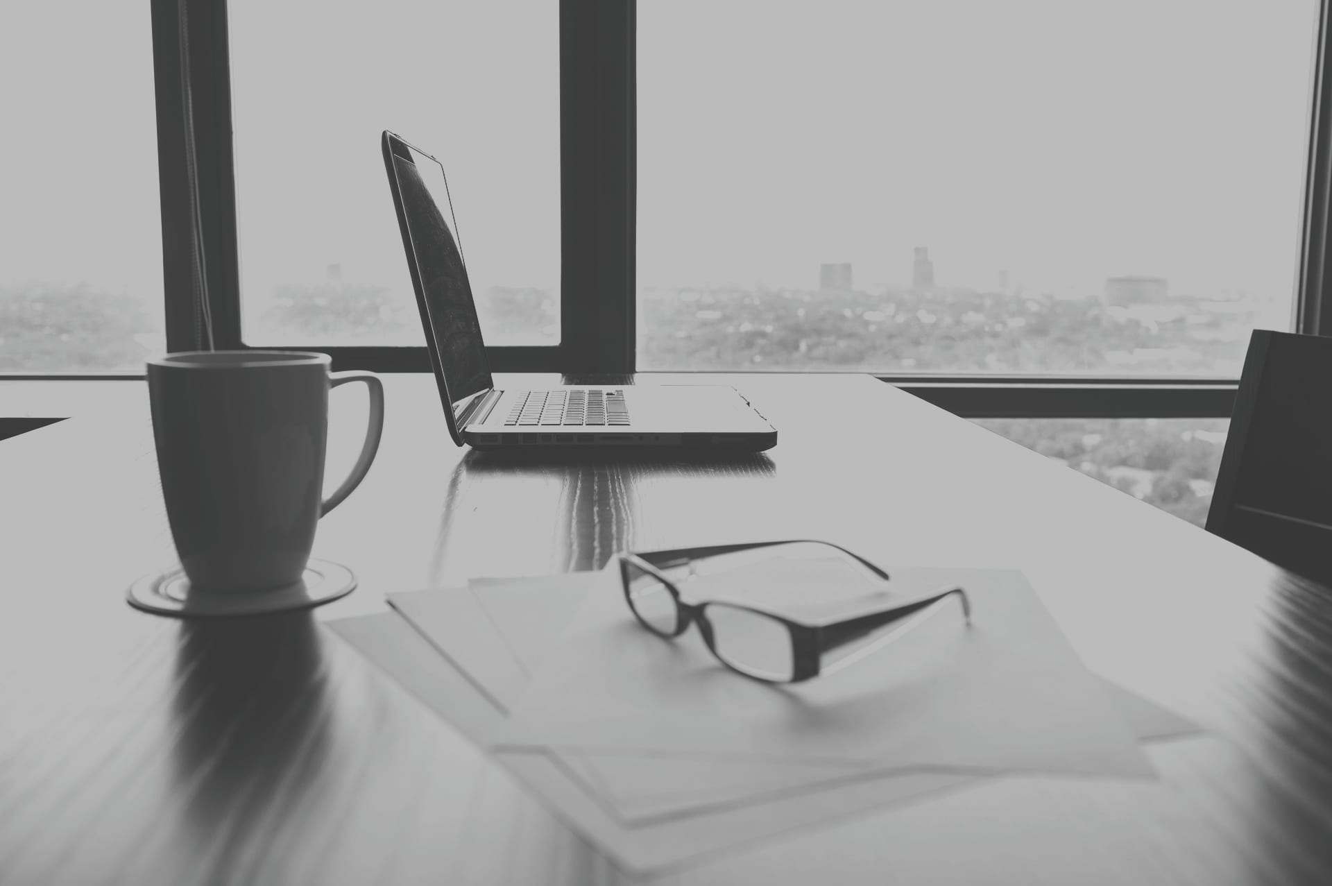 Desk with laptop, coffee mug and glasses on